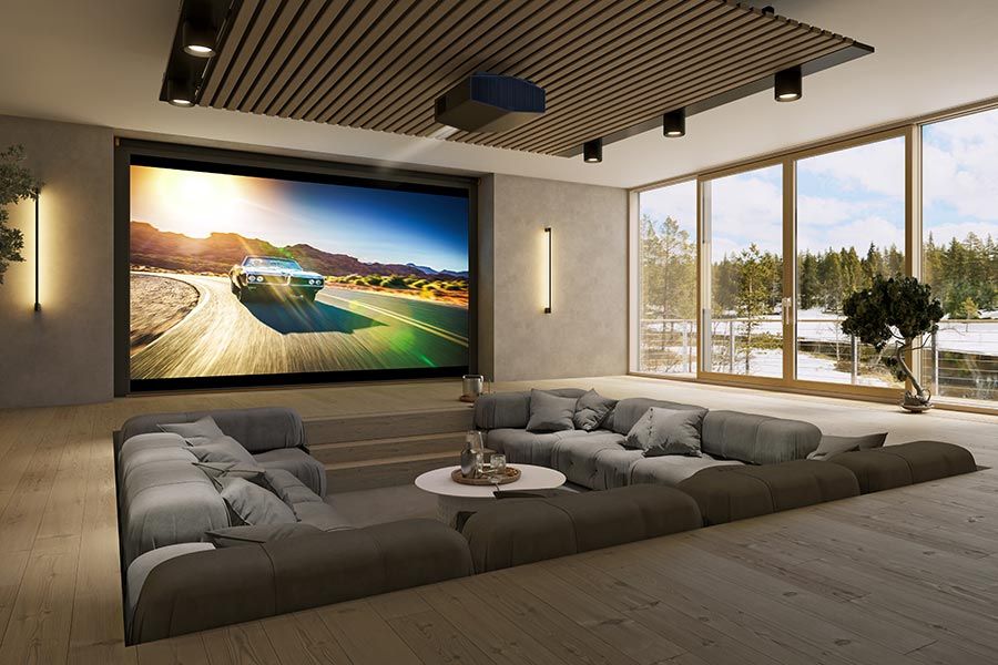 A modern home theater with a large screen showing a racing car scene, featuring sleek black theater chairs and ambient lighting.