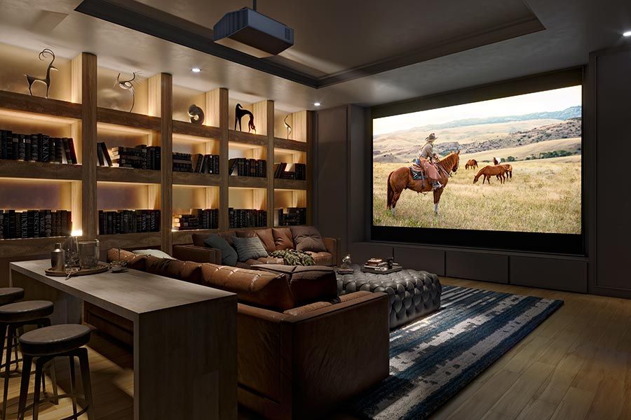 A cozy home theater with a large projection screen showing a western movie, surrounded by wood-paneled bookshelves and a comfortable sectional couch.